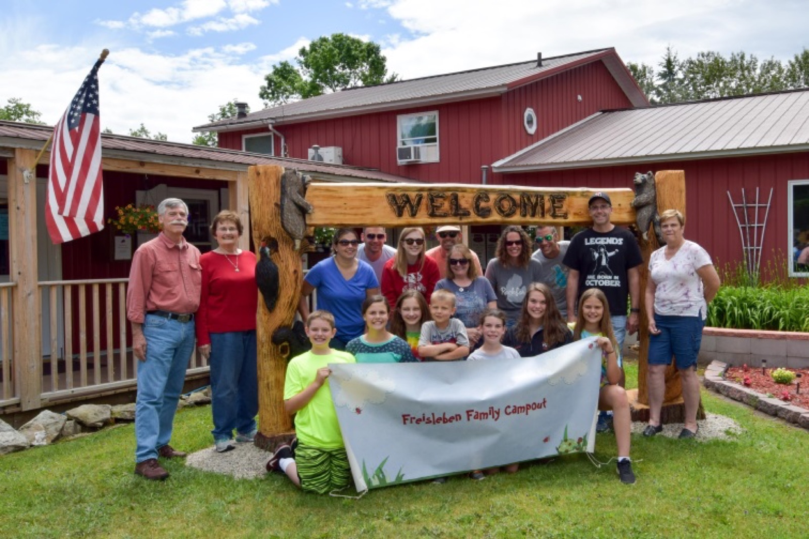 Campers gathered under the hand-carved welcome sign at Frontier Wilderness